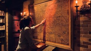 A woman points at a map in an escape room
