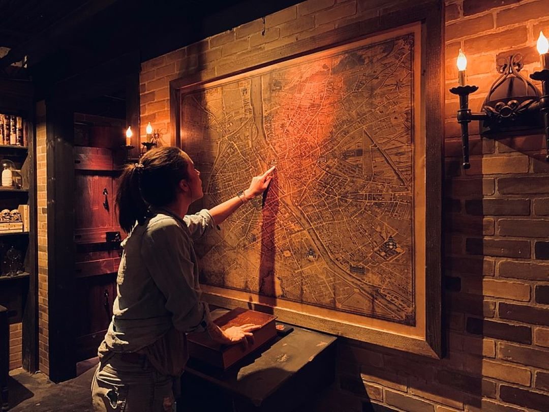A woman points at a map in an escape room