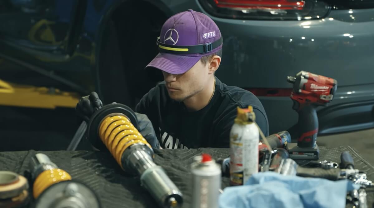 A tech works on a Porsche 718 Cayman S with Ohlins Road & Track coilovers. 